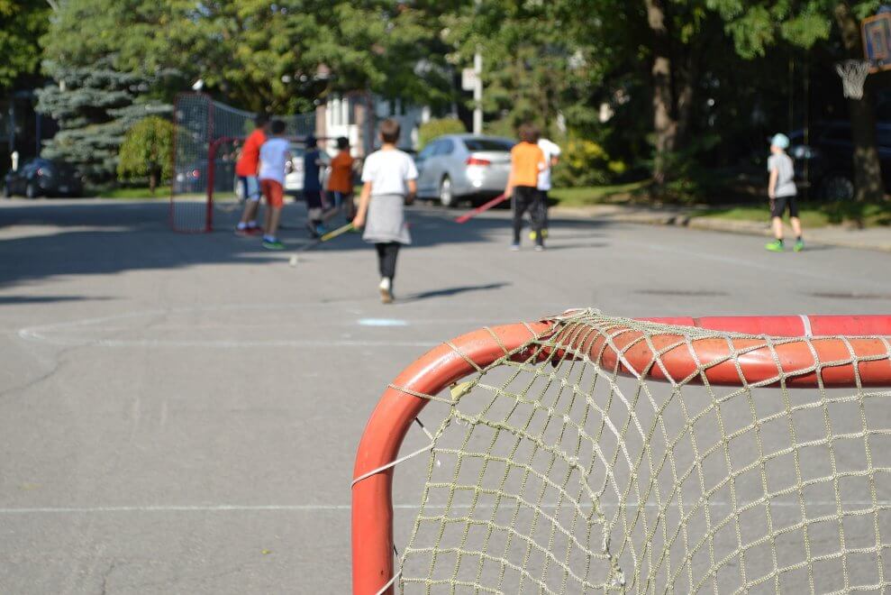 A group of kids plays street hockey on a warm spring day.