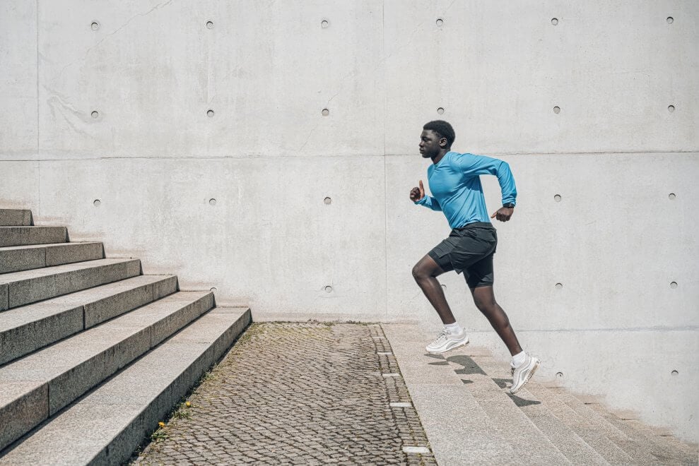 An elite athlete runs up a flight of stairs outdoors.