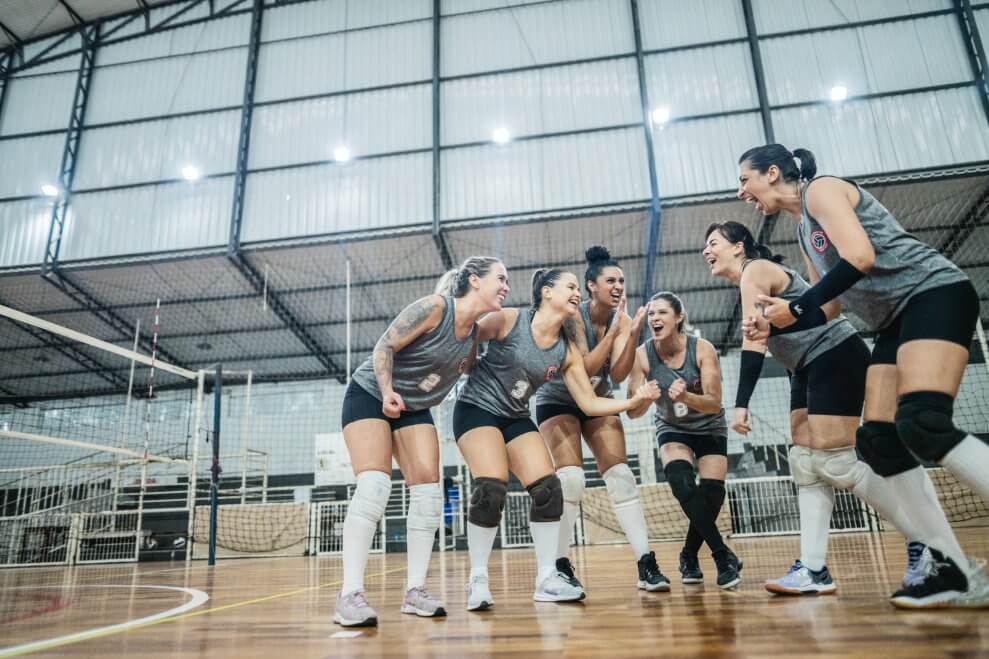 A women's volleyball team cheers on the court.