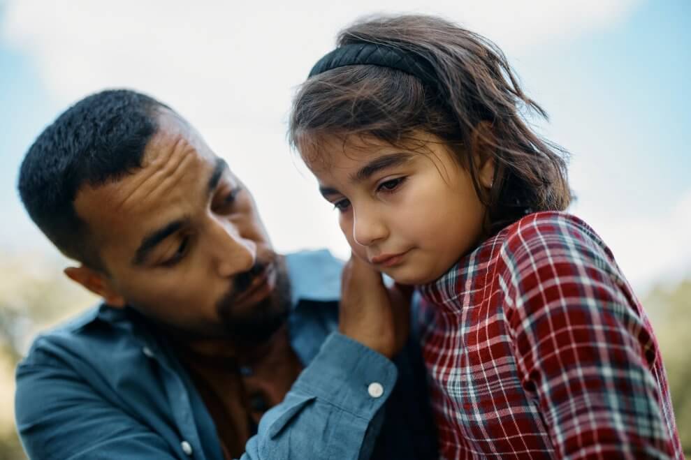 A dad comforts his crying daughter.