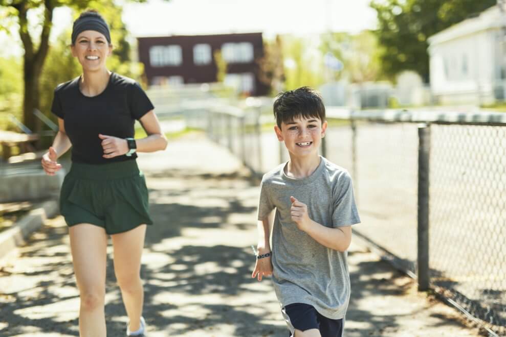 A mom and her son run outside on a sunny day.