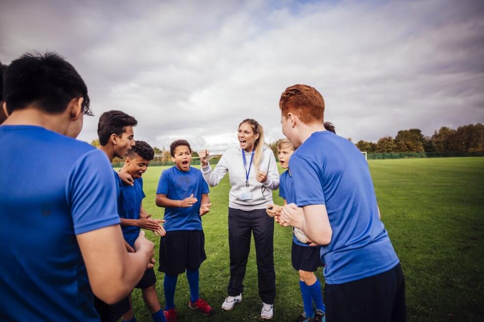 A coach leads her team in a cheer. 