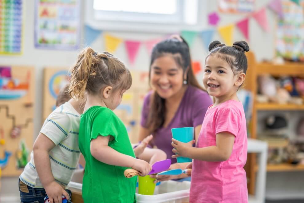 A early childcare educator plays with toddlers inside her centre.