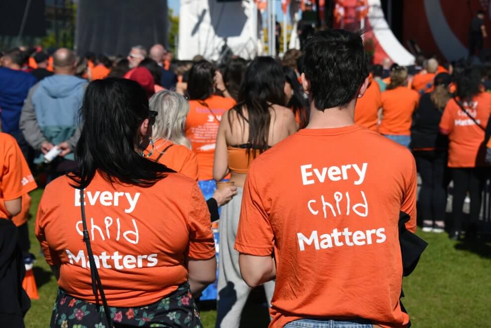 Two people wear orange "Every Child Matters" shirts at