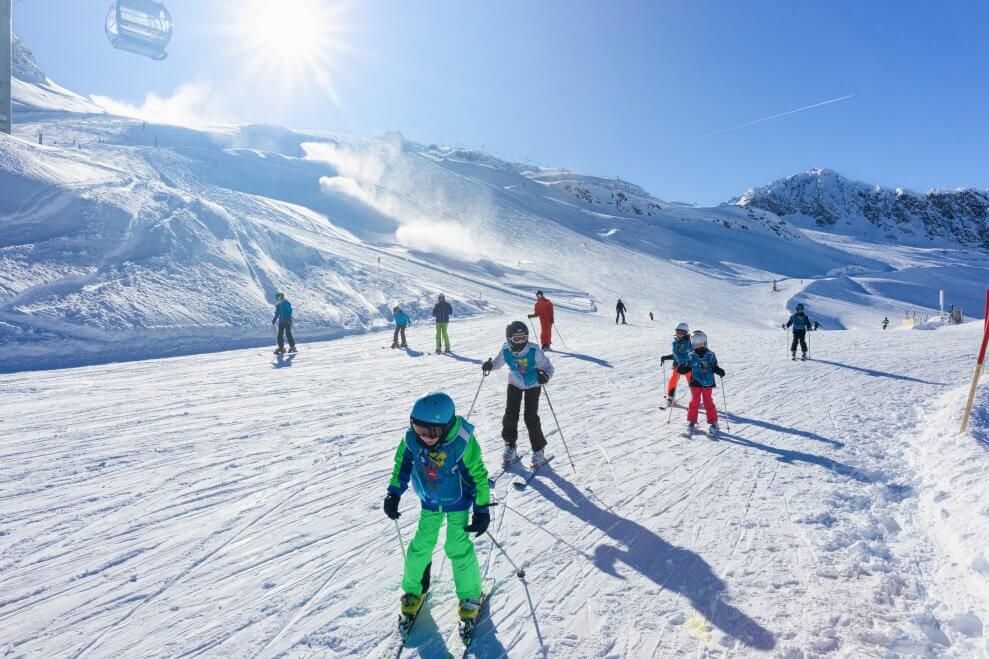 Children ski at a mountain ski resort on a sunny day.