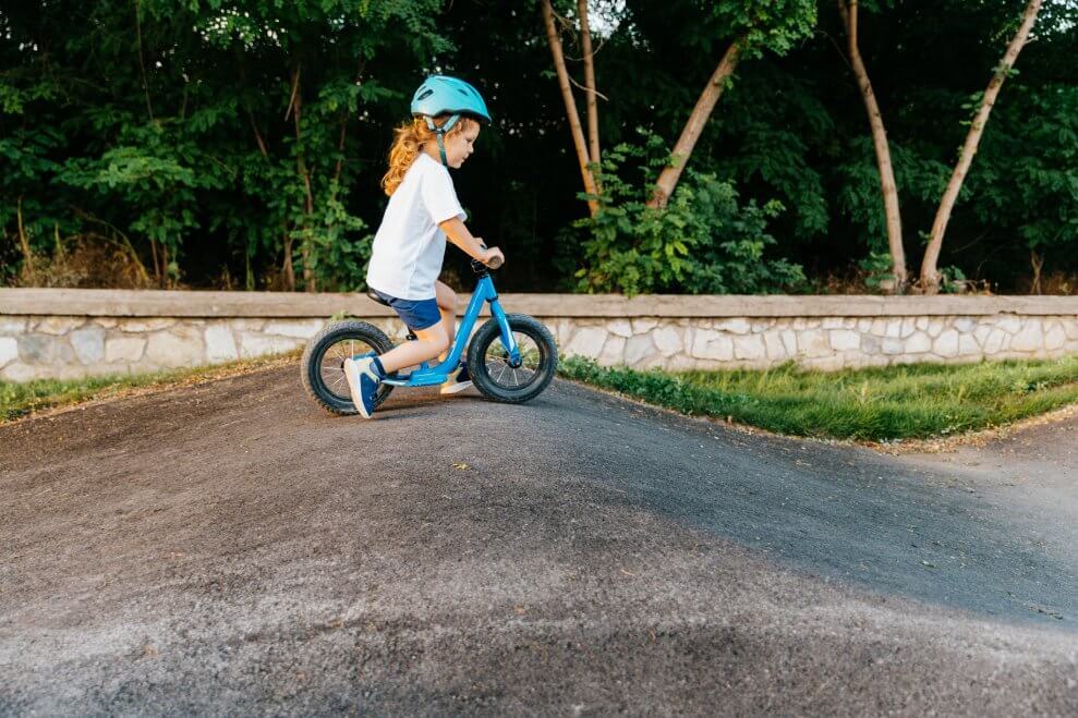 A toddler rides a balance bike at a bike park.