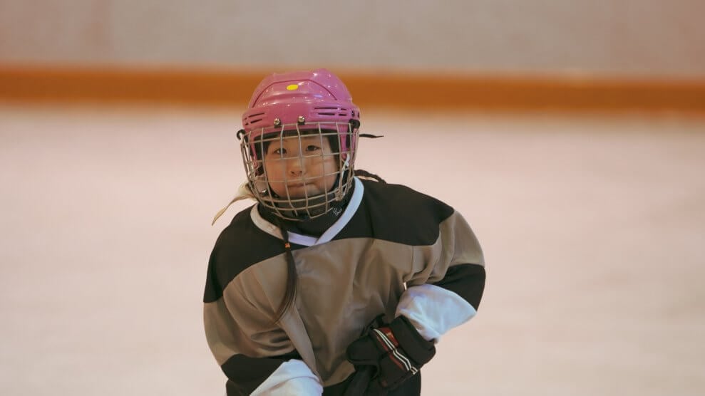 A young female hockey player skates around on an indoor rink. 