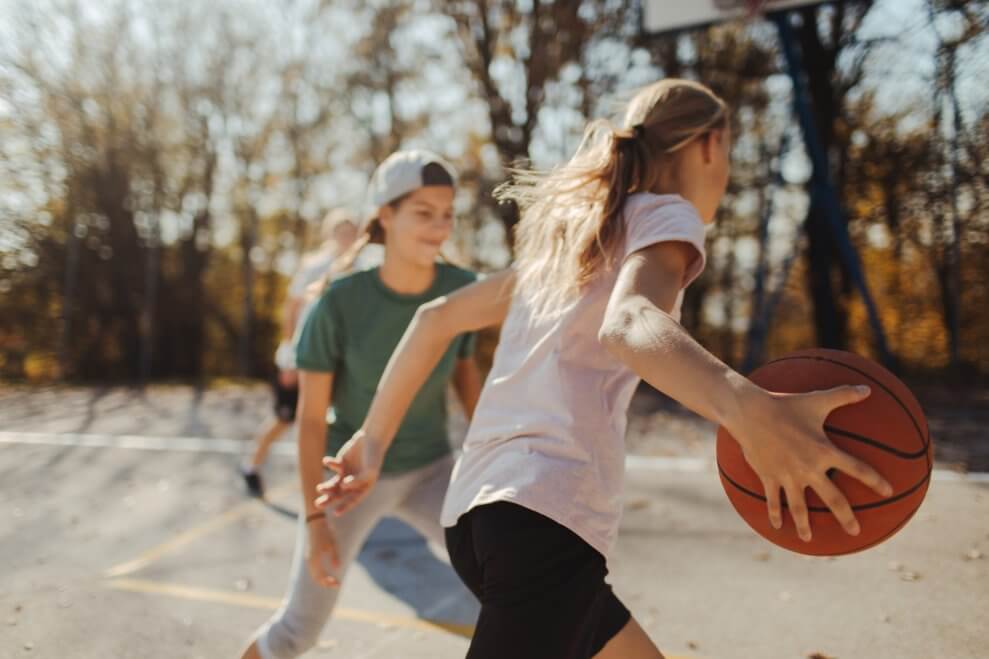 A group of girls plays basketball on an outdoor court.