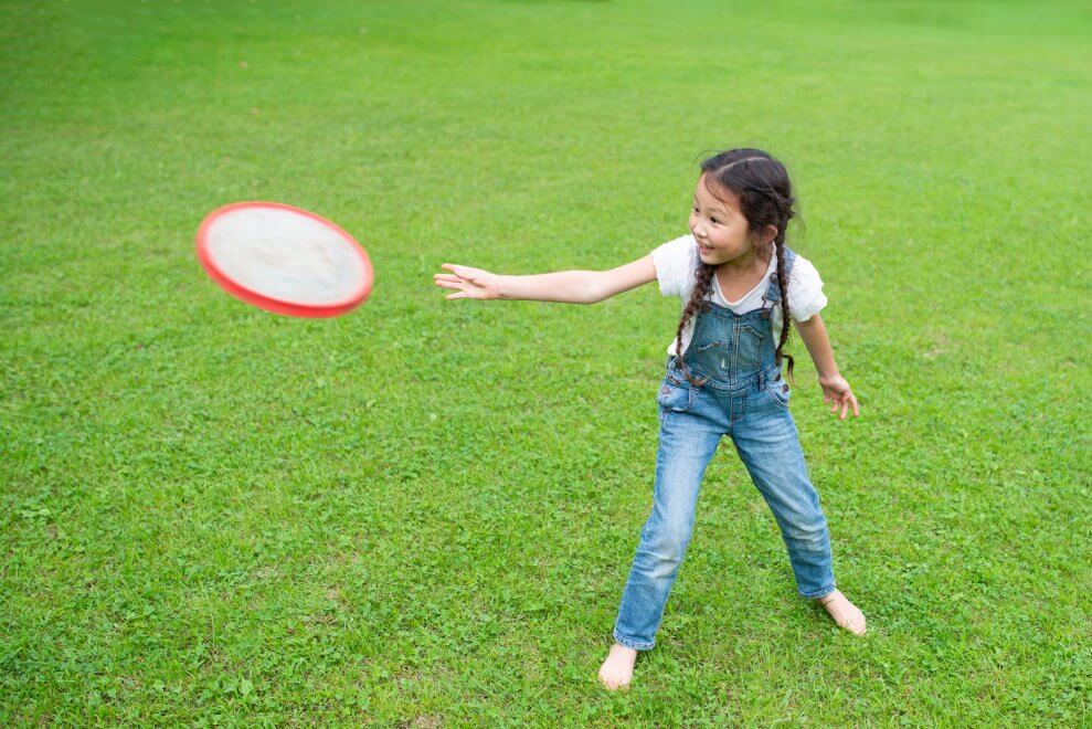 A girl tosses a frisbee in her backyard.
