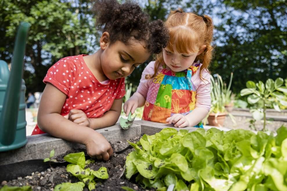Two young girls garden outside at a childcare centre.