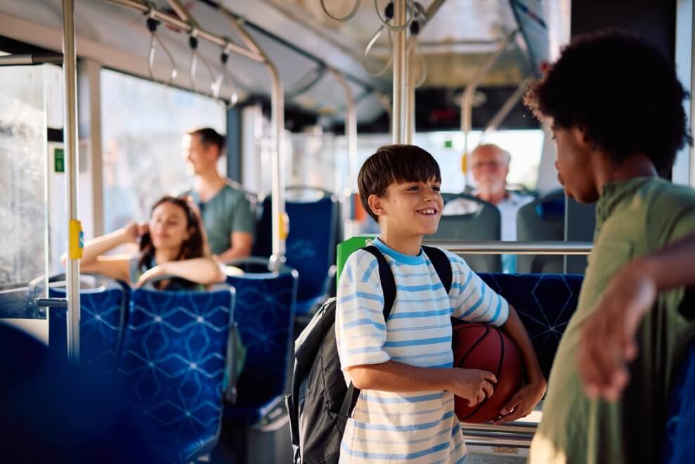 Two preteen boys talk as they ride a city bus on their way home from school.