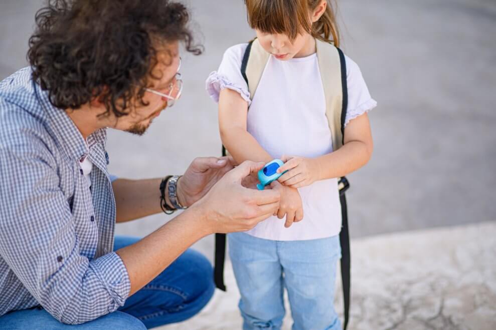 A father show his daughter how to use the smartwatch on her wrist.