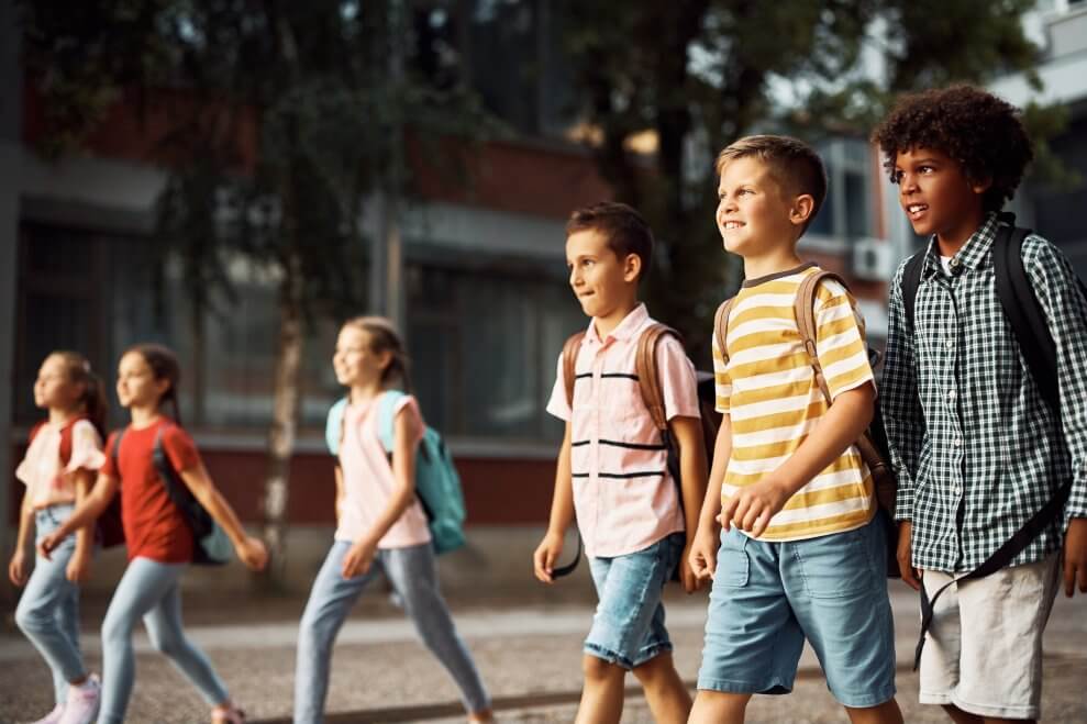 A group of kids walk to school together on a sunny morning.