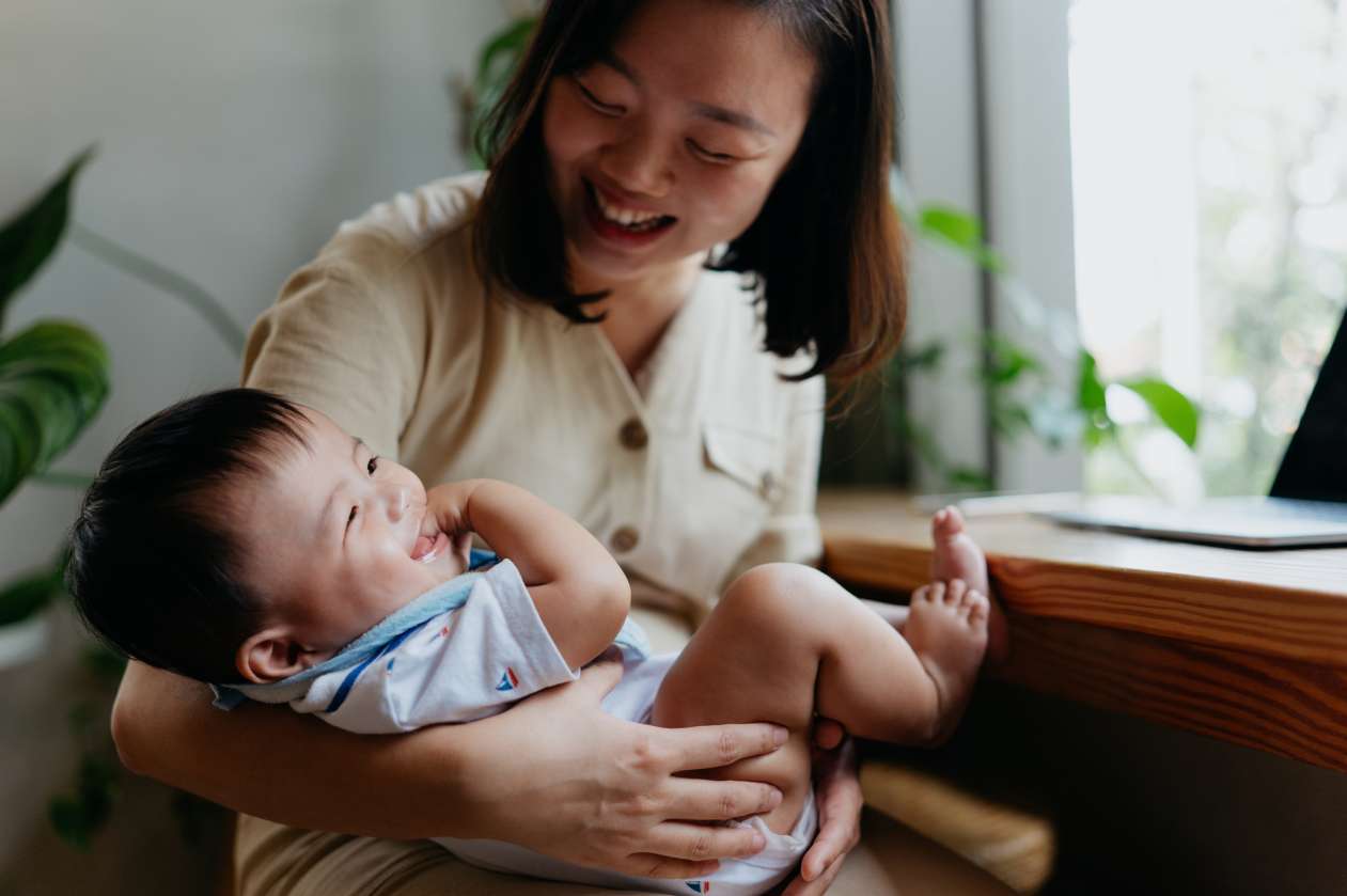 A mom rocks her baby as he smiles up at her. 
