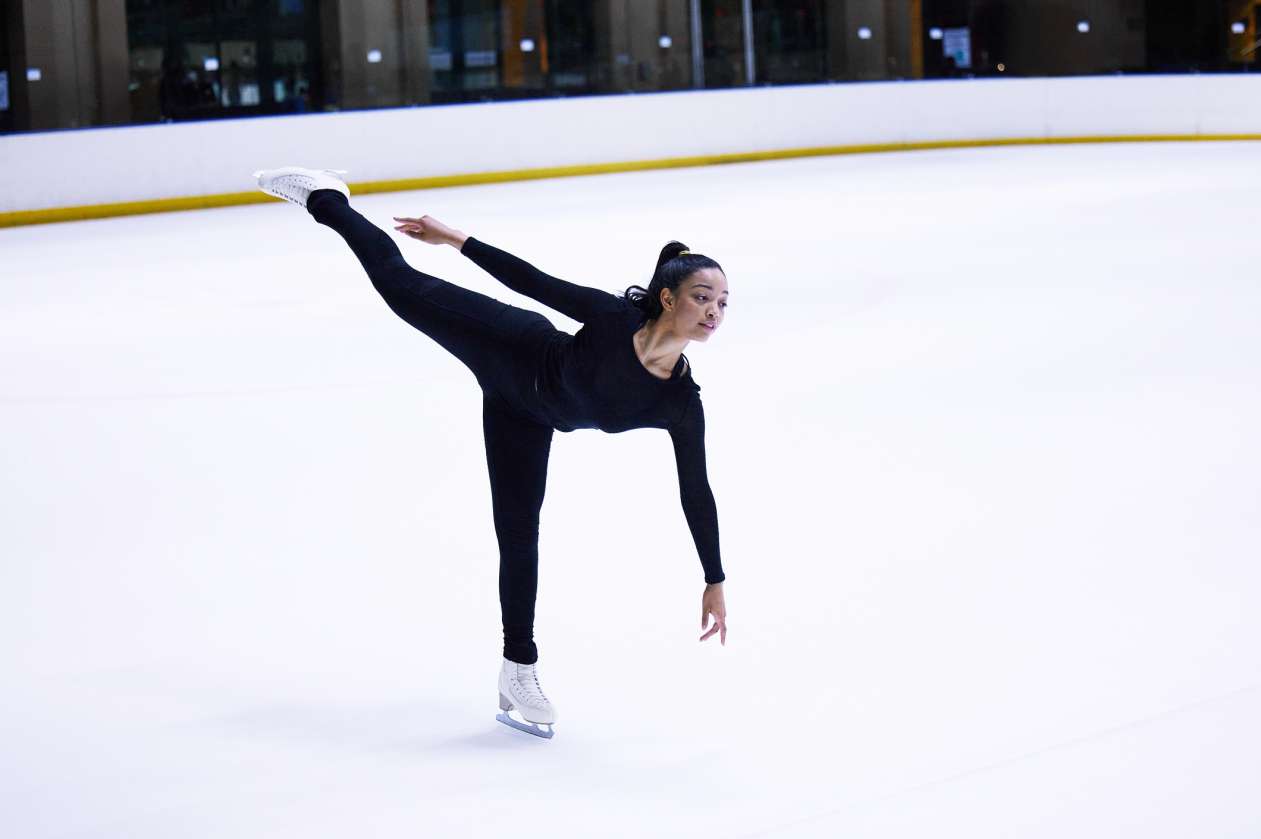 A woman figures skates on an indoor rink.