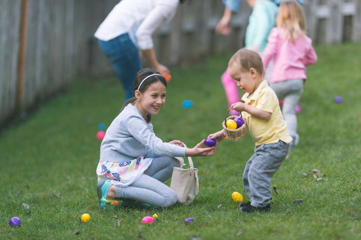 Two children collect eggs on the grass at a neighbourhood easter egg hunt.