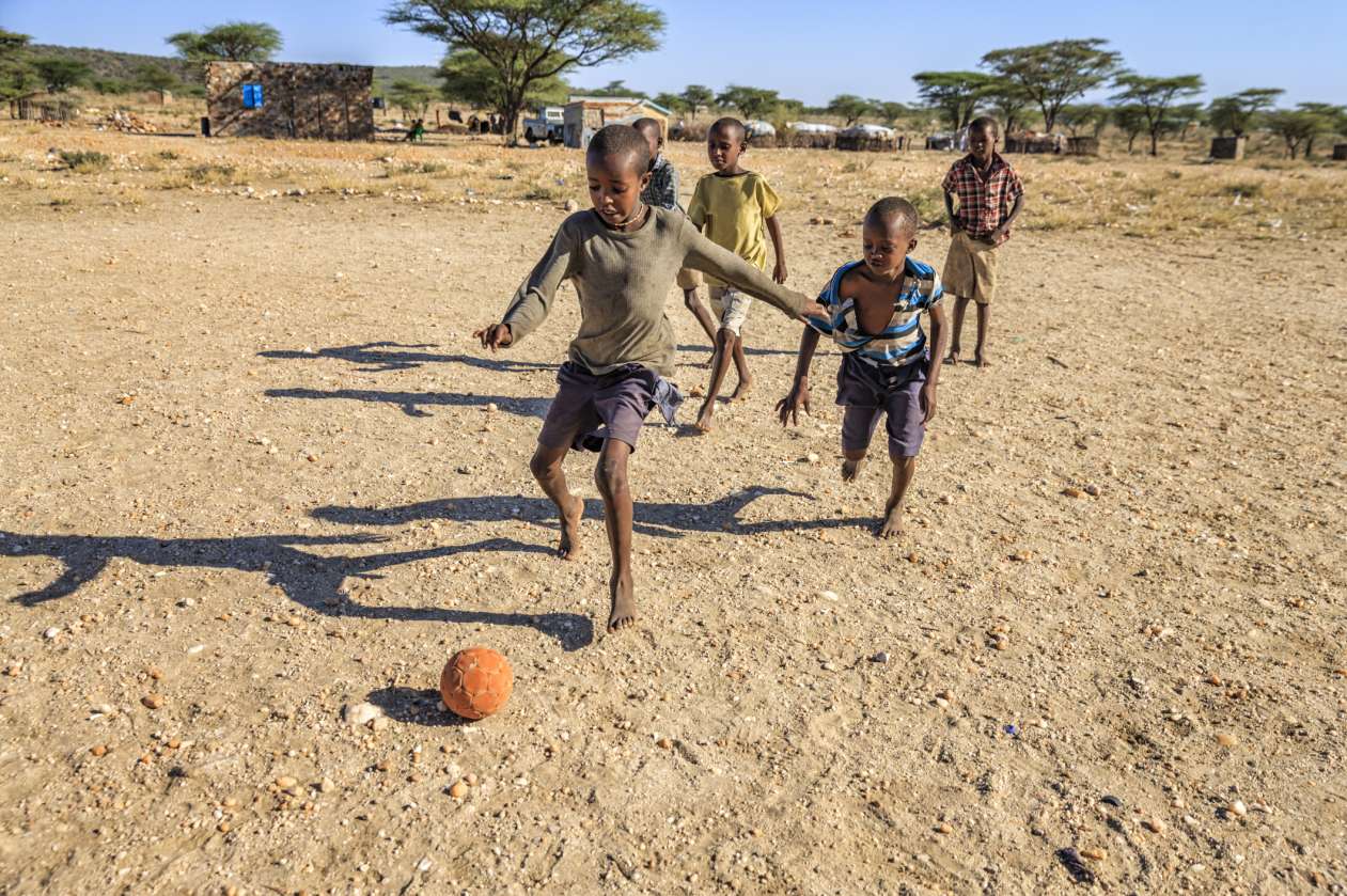 A group of boys plays soccer in their bare feet in Kenya.