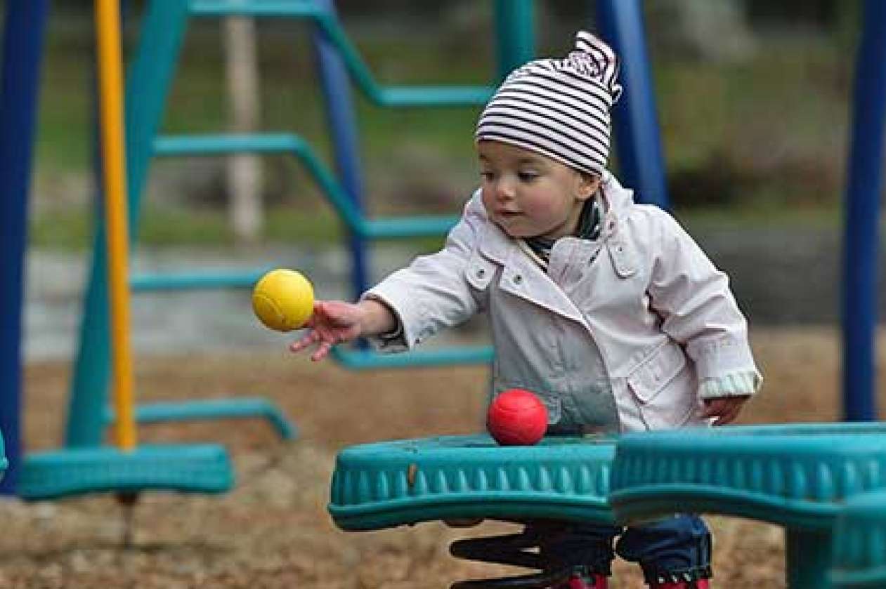 Young toddler throwing a ball in a playground