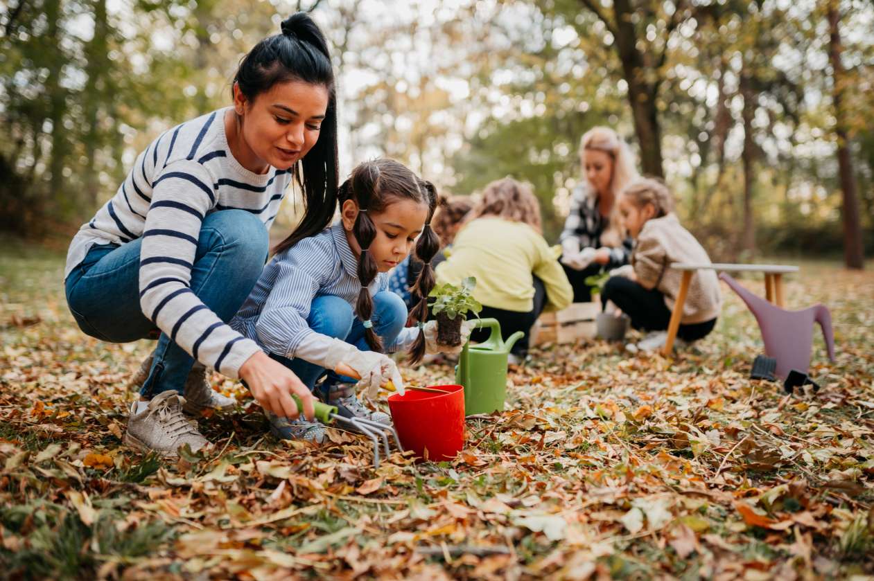 A group of school-age children plays outside with their teachers at a nature school.