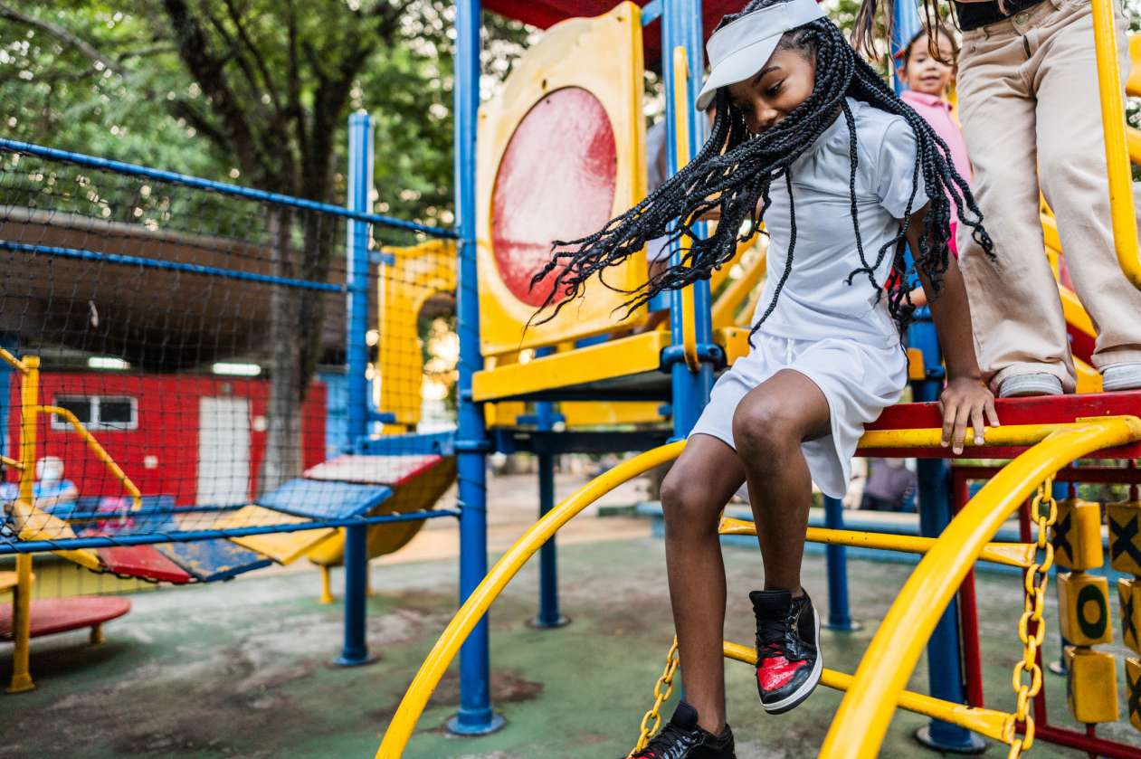 A girl climbs down off playground equipment.