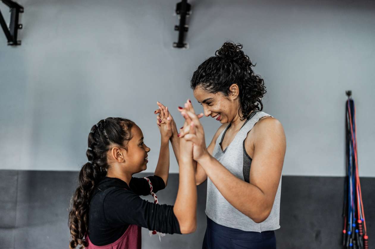A mom and her daughter high-five after working out together at a boxing gym.