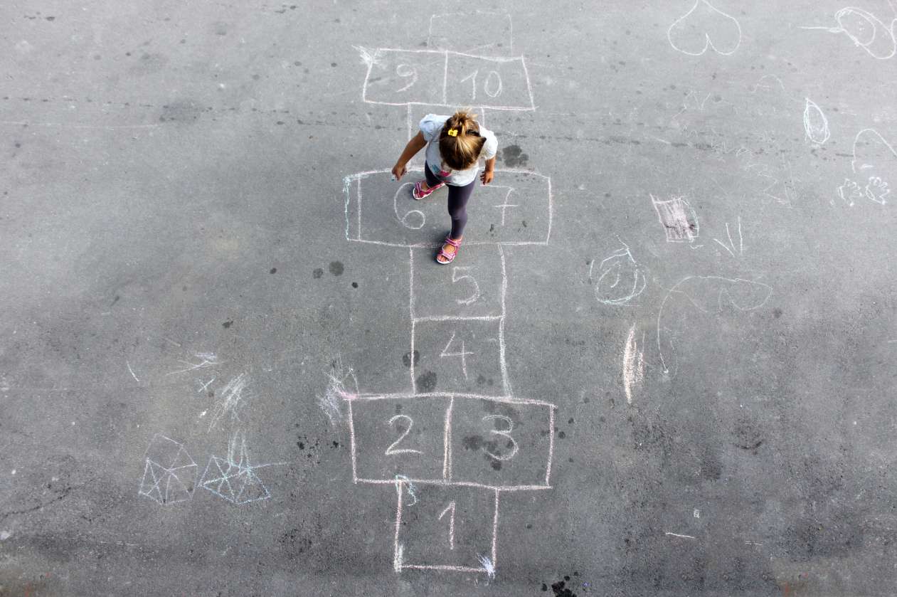 A girl plays hopscotch on the playground at recess.