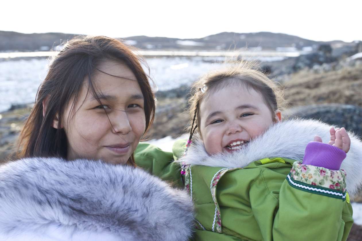 An Inuit mother holds her daughter on a sunny day in Nunavut.