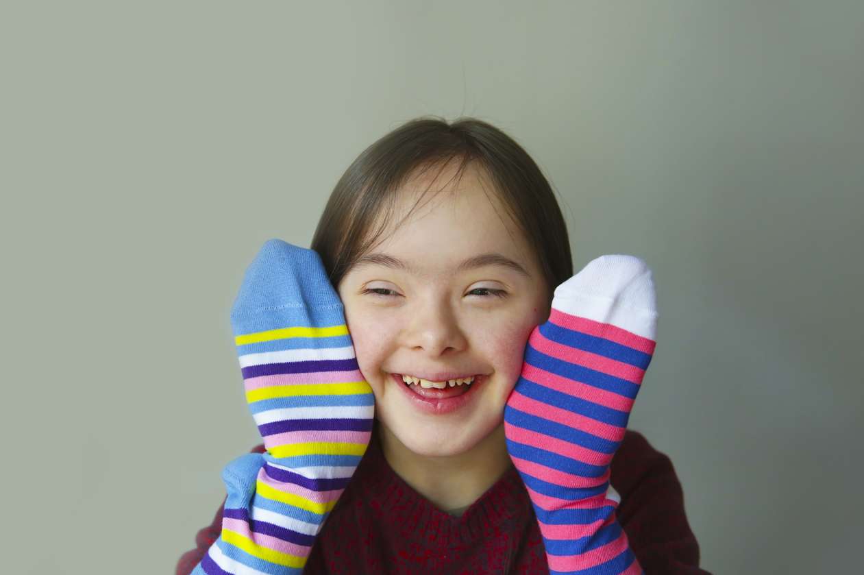 A girl smiles while wearing a sock on each hand.