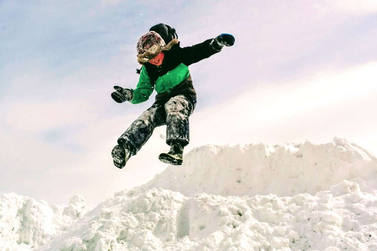 Boy jumping off snow bank