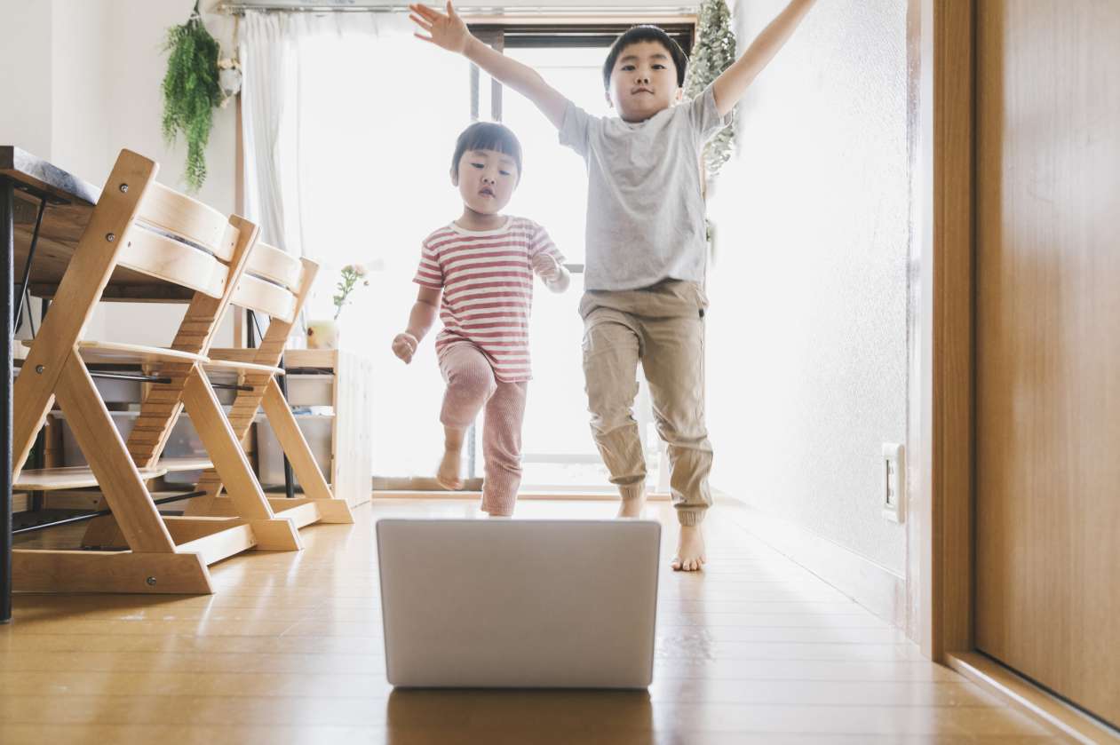 Two siblings dancing in front of a laptop in the kitchen