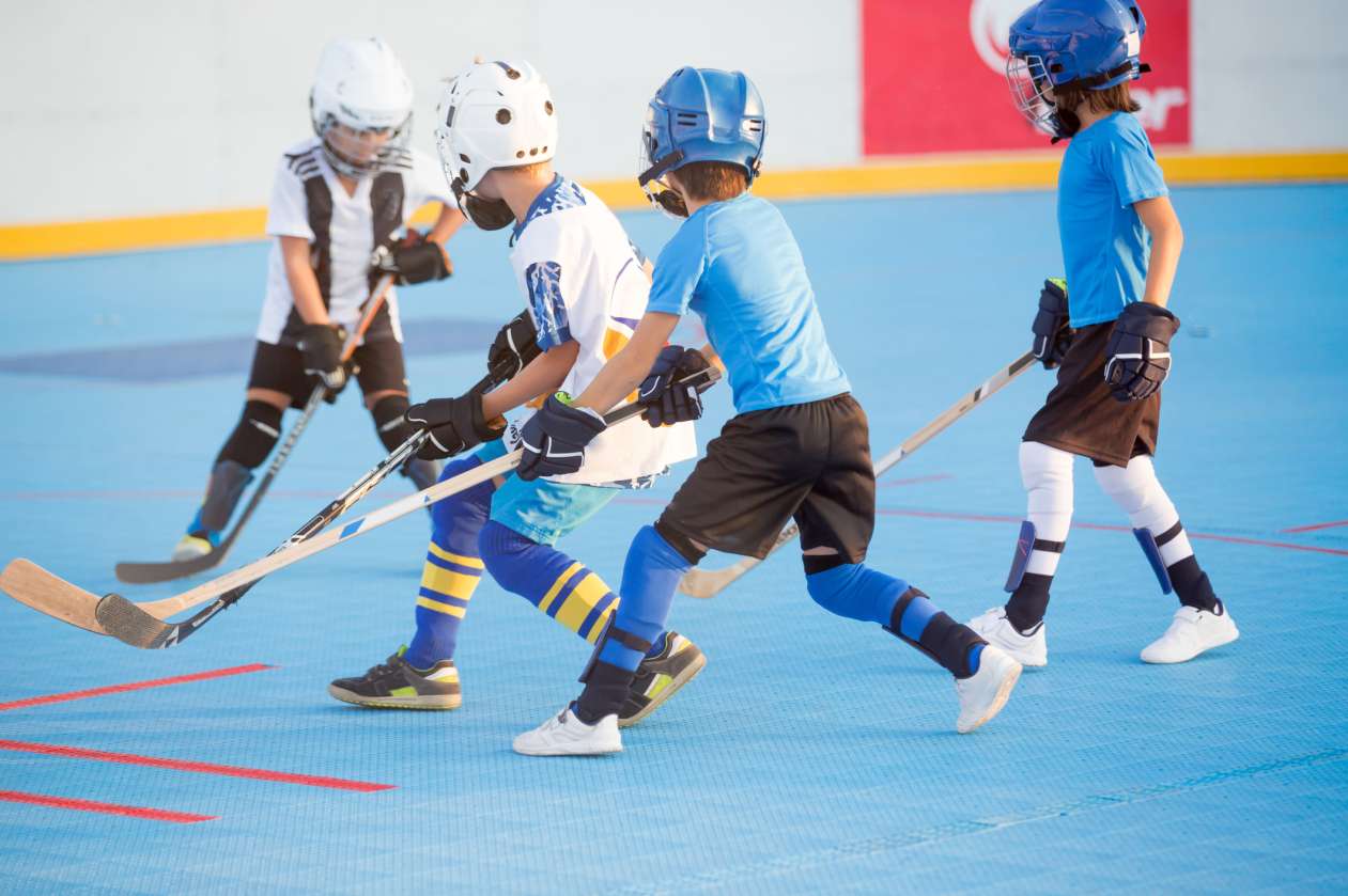 Group of children playing ball hockey on an indoor court