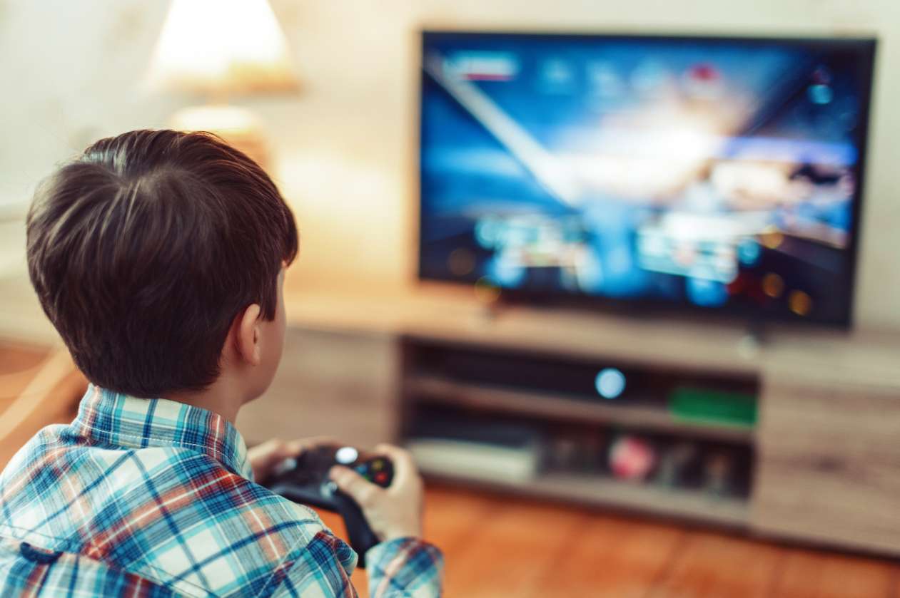 Boy sits in front of TV, holding video game controller