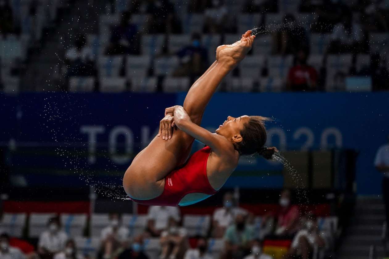 Olympic diver Jennifer Abel spins in the air, with her legs tucked into her chest, before entering the pool