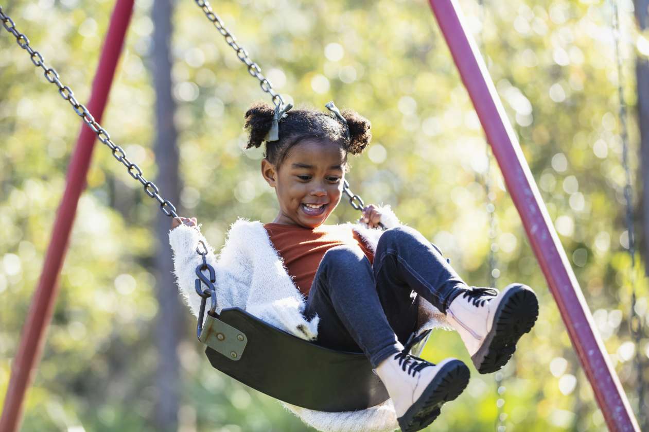 A young girl swings at an outdoor playground.