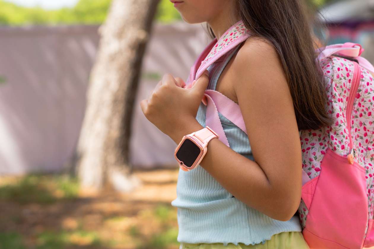 An elementary-age girl wears a smartwatch and a backpack.